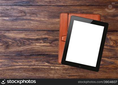 tablet pc with blank screen and brown case on wooden background, top view