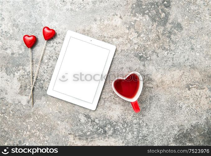 Tablet PC with red hearts decoartion and cup of tea. Valentines Day concept with space for your text and image