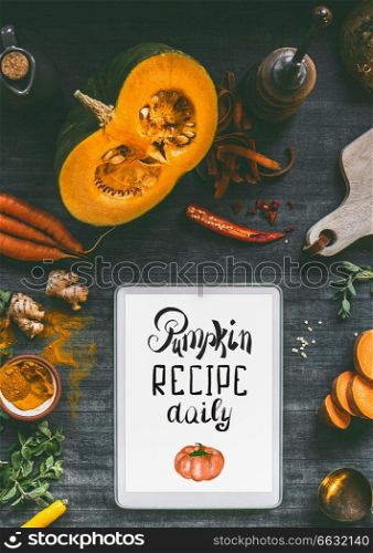 Tablet pc with text lettering  Pumpkin recipe daily. Orange cooking ingredients  sweet potato, carrots, turmeric powder,chili and ginger for tasty cuisine. Healthy and clean vegetarian food and eating