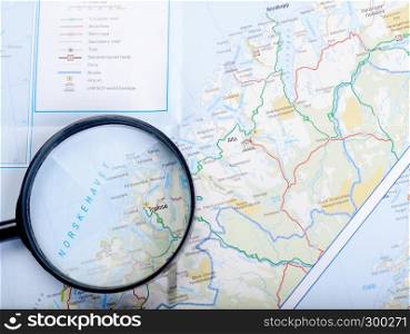 Tablet with a white screen, black magnifier lying on the map of the Norwegian fjords. Map, magnifier and tablet
