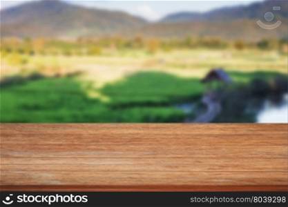 Tabletop wooden with green rice field blurred background, stock photo