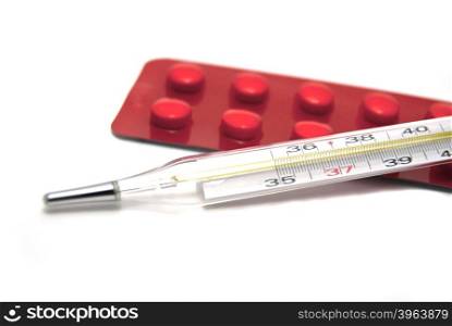 Tablets and thermometer on white background