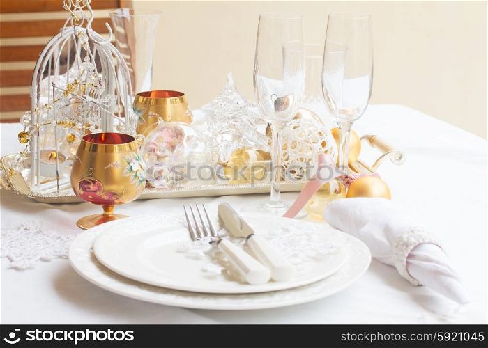 Tableware for christmas - set of plates, cups and utencils with white table cloth and christmas golden decorations