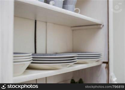 Tableware on a wooden shelf, plates and cups in a closet close-up. Tableware on a wooden shelf, plates and cups in a closet