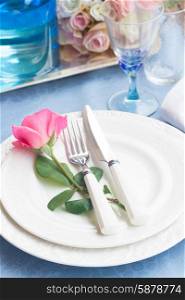 Tableware - set of plates, cups and utencils with rose on blue tablecloth