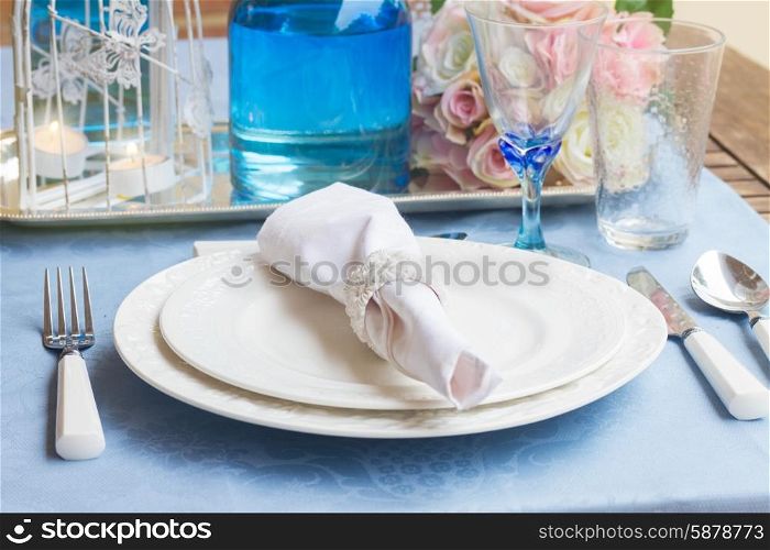 Tableware - set of white plates, glasses and utencils on blue tablecloth