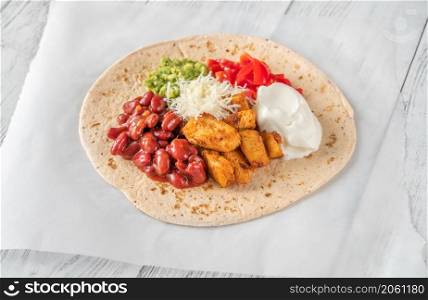 Taco with chicken and vegetable filling on the wooden background