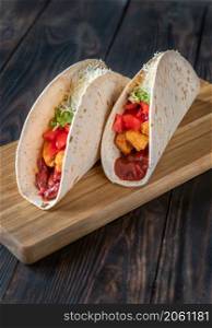 Taco with chicken and vegetable filling on the wooden background
