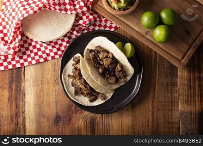 Tacos de Bistec. Homemade grilled meat in a corn tortilla. Street food from Mexico, traditionally accompanied with cilantro, onion and spicy sauce or guacamole