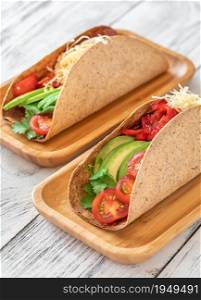 Tacos with ham and vegetables on the serving wooden plate