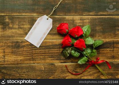 Tag template next to a red bouquet of roses on a rustic wood background