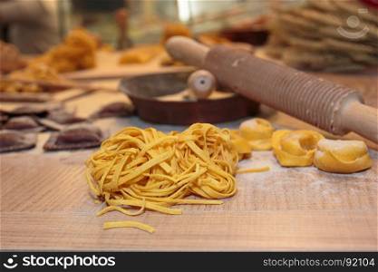 Tagliatelle and Tortellini Italian Pasta with Flour and Cutter Rolling Pin on Wooden Table