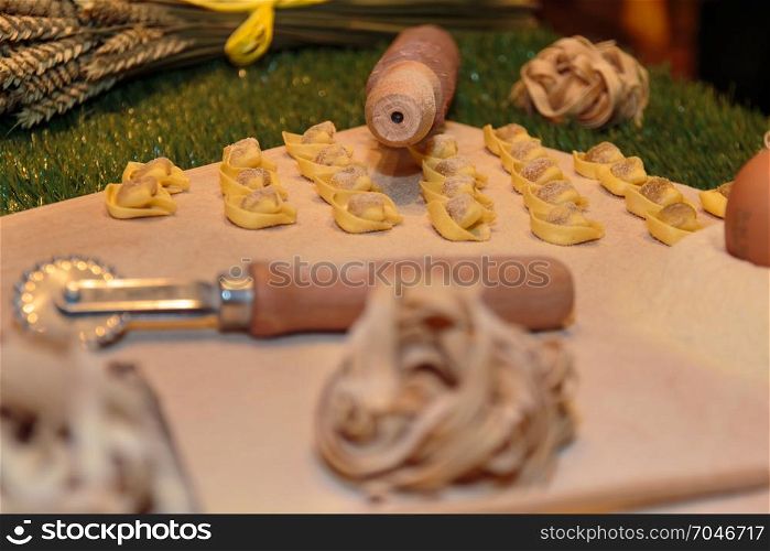 Tagliatelle and Tortellini Italian Pasta with Flour and Pastry Cutter on Table