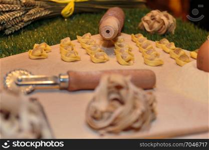 Tagliatelle and Tortellini Italian Pasta with Flour and Pastry Cutter on Table