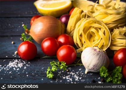 tagliatelle dry pasta with tomatoes and spices on blue wooden background