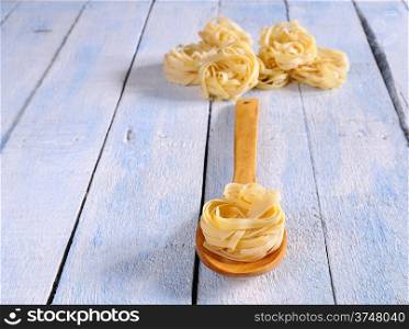 Tagliatelle in a spoon on the kitchen table.