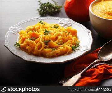 Tagliatelle pastawith pumpkin cream sauce over black background.. Tagliatelle pasta with pumpkin cream sauce over black background