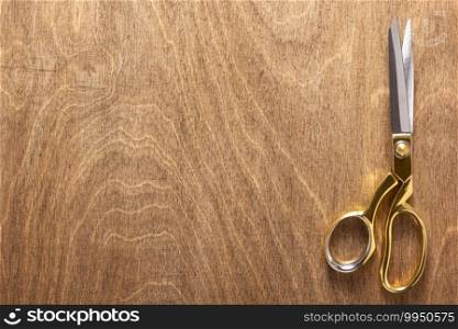 tailor or sewing scissors on wooden table background, flat lay top view