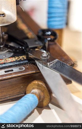 Tailor's scissors, buttons and blue yarn next to old sewing machine