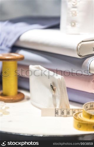 Tailor's Table with Thread and Tape Measure and Shirt Cloth Swatches