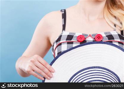 Tailoring, patterns concept. Woman wearing retro checked black and white dress with two red buttons holding sun hat. Checked dress, red buttons and sun hat
