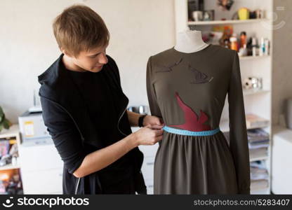 tailoring, sewing and clothing concept - fashion designer with dummy and measuring tape making new dress at home studio or workshop. fashion designer with dummy making dress at studio