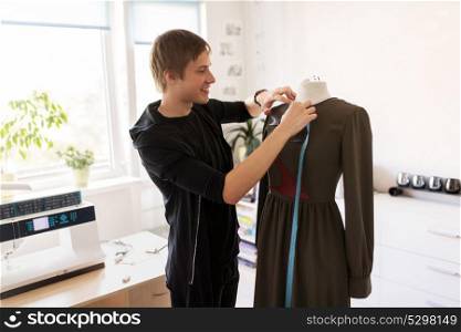 tailoring, sewing and clothing concept - fashion designer with dummy and measuring tape making new dress at home studio or workshop. fashion designer with dummy making dress at studio