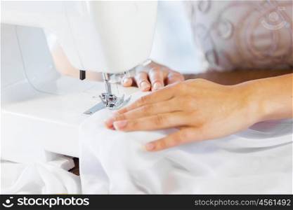 Tailors studio. Close up of woman dressmaker hands working with sewing machine