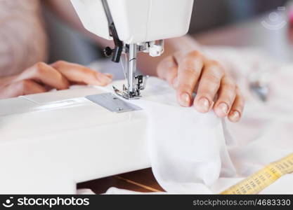 Tailors studio. Close up of woman dressmaker hands working with sewing machine