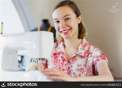 Tailors studio. Young attractive woman dressmaker working with sewing machine