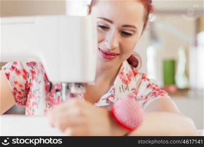 Tailors studio. Young attractive woman dressmaker working with sewing machine