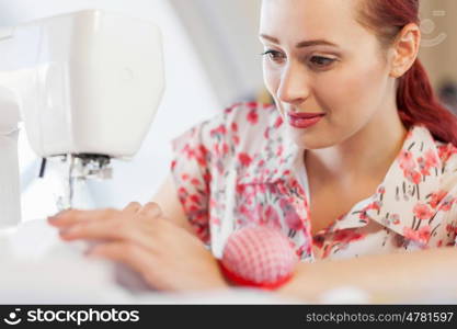 Tailors studio. Young attractive woman dressmaker working with sewing machine