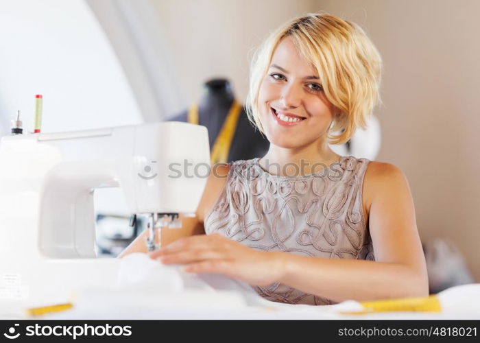 Tailors studio. Young attractive woman dressmaker working with sewing machine