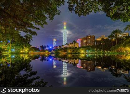 Taipei park garden and reflection of skyscrapers buildings. Financial district and business centers in smart urban city at night, Taiwan.