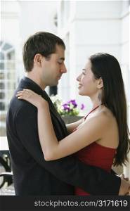 Taiwanese mid adult woman and Caucasian man embracing and gazing into each others eyes.