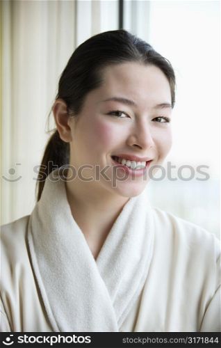 Taiwanese mid adult woman in bathrobe smiling at viewer.
