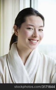 Taiwanese mid adult woman in bathrobe smiling at viewer.