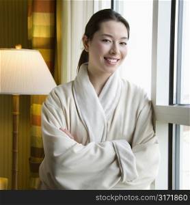 Taiwanese mid adult woman in bathrobe smiling at viewer with arms crossed.