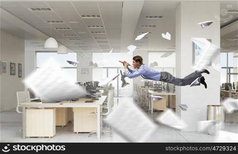 Take a break and relax. Young businessman flying in office and playing fife
