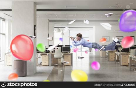Take a break and relax. Young businessman flying in office and playing fife