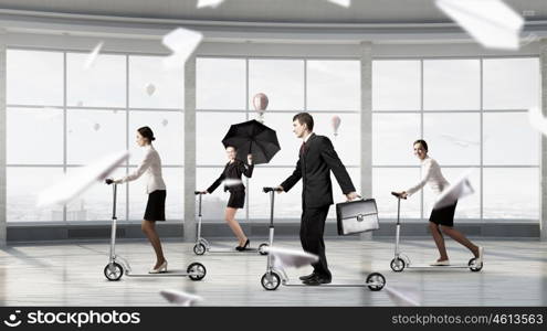 Take a five minute break. Young cheerful businesspeople riding scooter in office