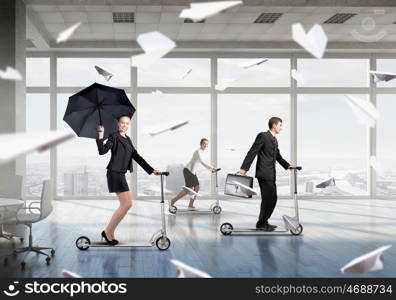 Take a five minute break. Young cheerful businesspeople riding scooter in office