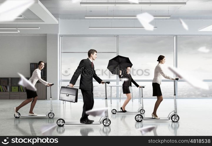 Take a five minute break. Young cheerful businesspeople riding scooter in office