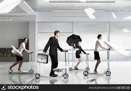 Take a five minute break. Young cheerful businesspeople riding scooter in office