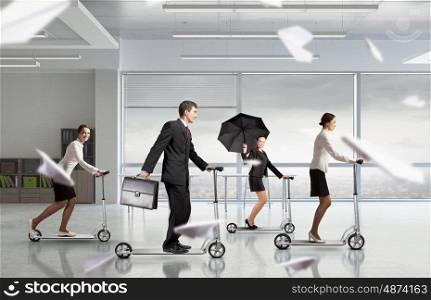 Take a five minute break. Young cheerful businesspeople riding scooter in office