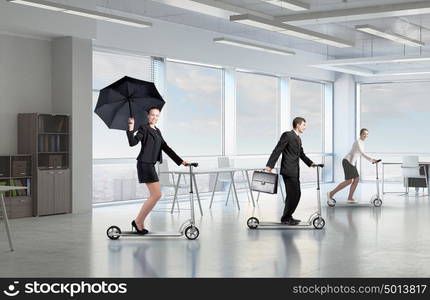 Take a five minute break. Young cheerful businesspeople riding scooter in office