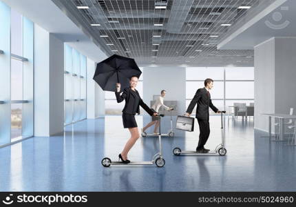 Take a five minute break. Young cheerful businesspeople riding scooter in office