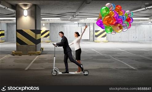 Take a five minute break. Young cheerful businesspeople riding scooter in underground parking