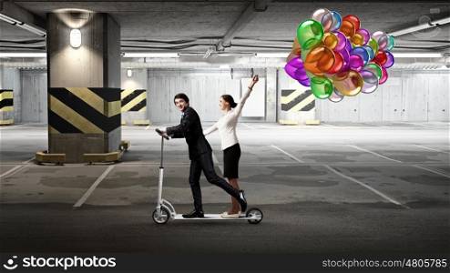 Take a five minute break. Young cheerful businesspeople riding scooter in underground parking