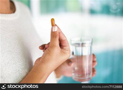 Take a medicine health care and people concept / woman holding pill capsule supplementary food and taking with water glass in hand
